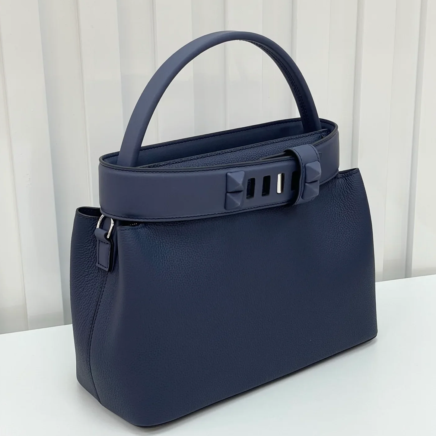 Deep Navy Blue Curved Structured Handbag With Geometric Pyramid Trim Accents And Rounded Smooth Top Carry Handle